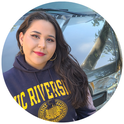 Photo of Samantha Acosta, a UCR student smiling at the camera with a car hood in the background