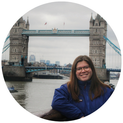 Photo of Laura Gimenz Anglada, a UCR student with brown hair who is smiling at the camera with the London Bridge and the Thames River behind her